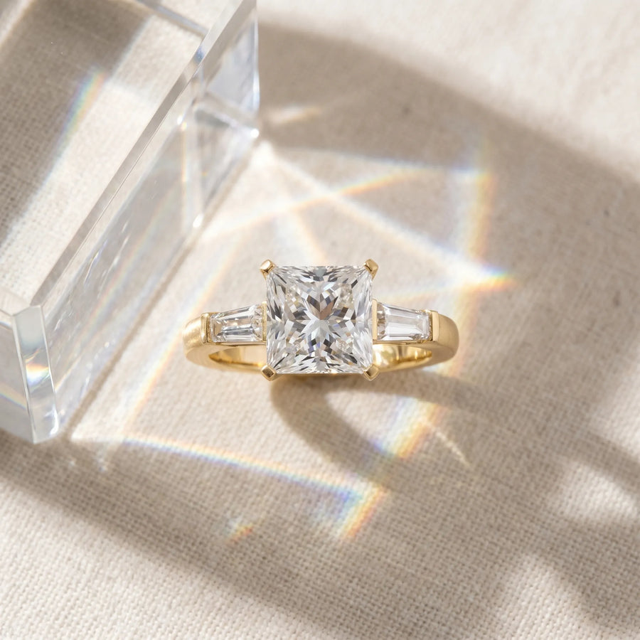Yellow gold Princess Solitaire with Tapered Baguette Side Stones on a Classic Band with Four-Prong Setting