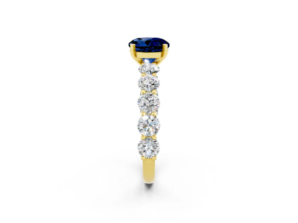 Yellow gold Round Cut Blue Sapphire Prong Setting with Side Stones on a Pave Band