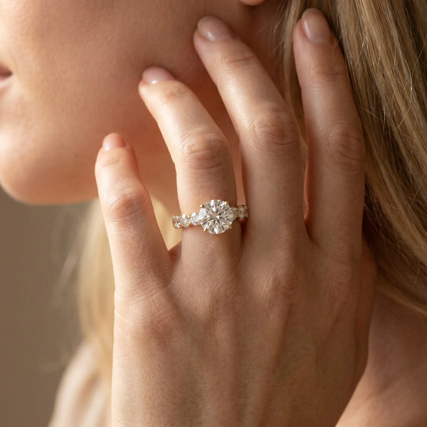 Yellow gold Round Cut Diamond Prong Setting with Side Stones on a Pave Band