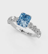 White gold Fancy Blue Radiant Cut Diamond Prong Setting with Side Stones on a Pave Band