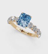Yellow gold Fancy Blue Radiant Cut Diamond Prong Setting with Side Stones on a Pave Band