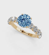 Yellow gold Fancy Blue Round Cut Diamond Prong Setting with Side Stones on a Pave Band