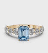 Yellow gold Fancy Blue Emerald Cut Diamond Prong Setting with Side Stones on a Pave Band